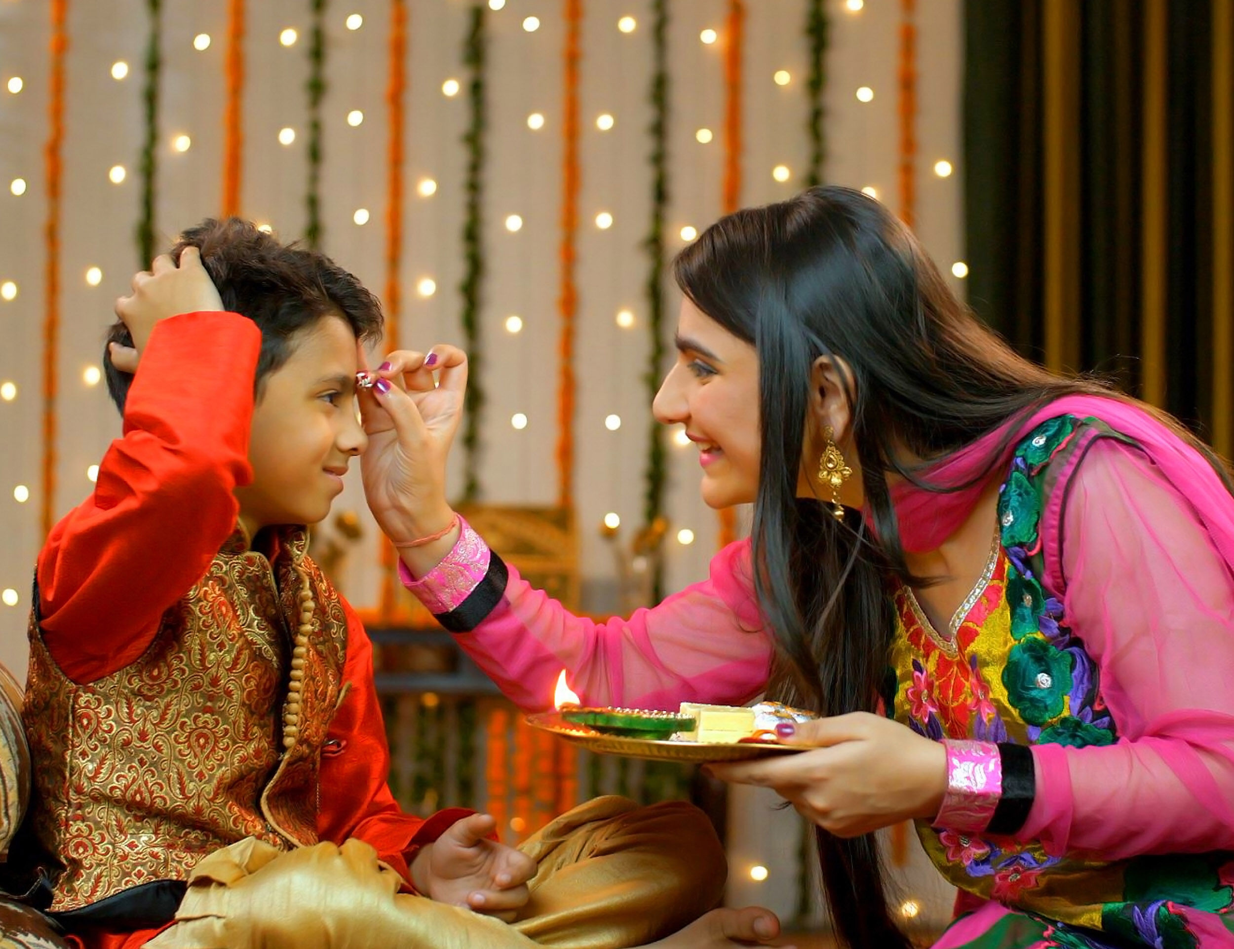 Sister performing the essential tika ceremony ritual on her brother's forehead for the Bhai Dooj festival.